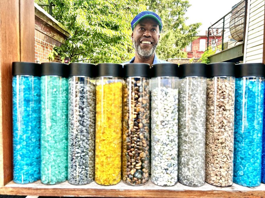 A row of tall jars filled with colored sand, gravel and stone