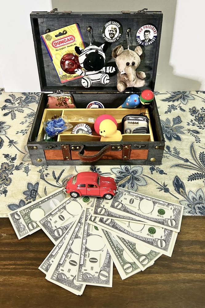 An open trunk of small prizes with play money fanned out in front of it