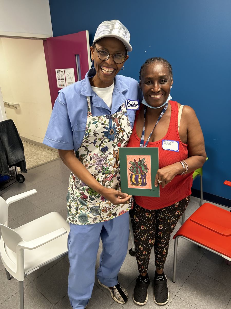 A Kiddo and a resident smiling, holding up a finished framed picture