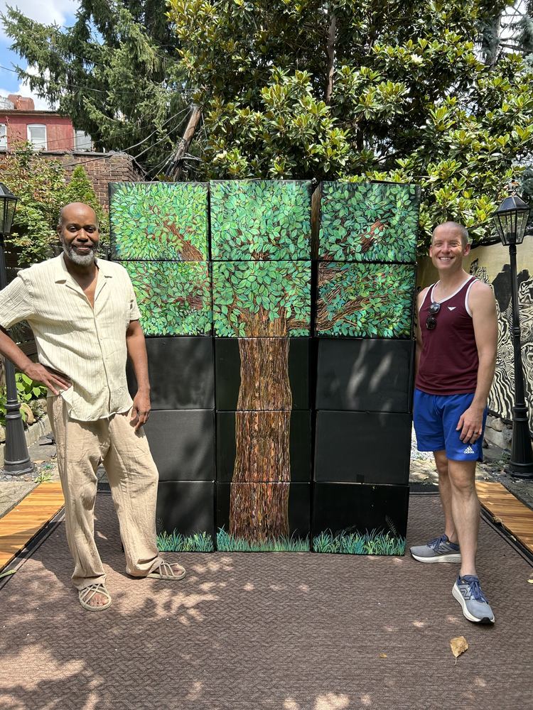 Two men standing either side of a large seasonal tree built from cubes