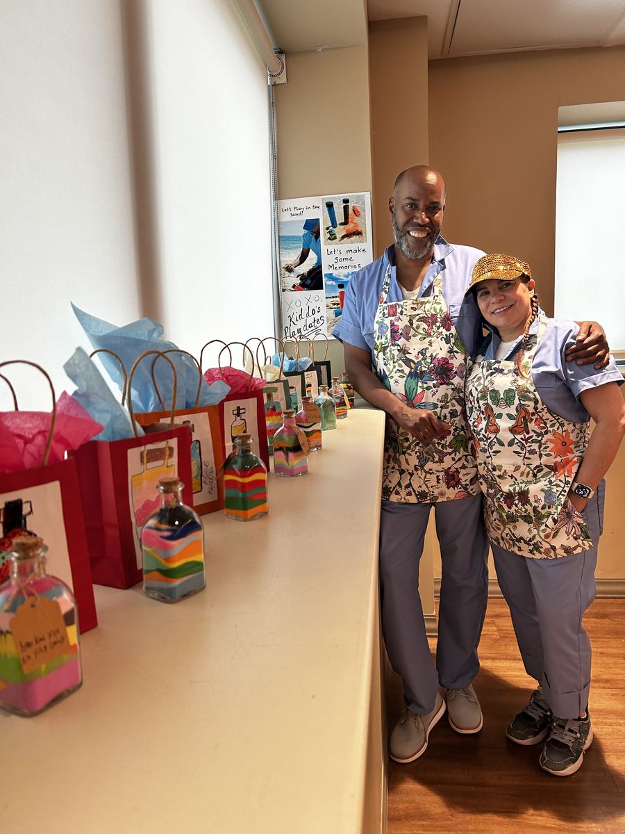 Two Kiddos beside a table of gift bags and finished sand bottles
